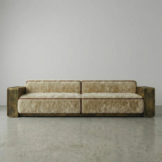 Front view of the Peau Sofa by Diamant Versatile, with cream furry upholstery, brown trim and broad gold-toned metal armrests.