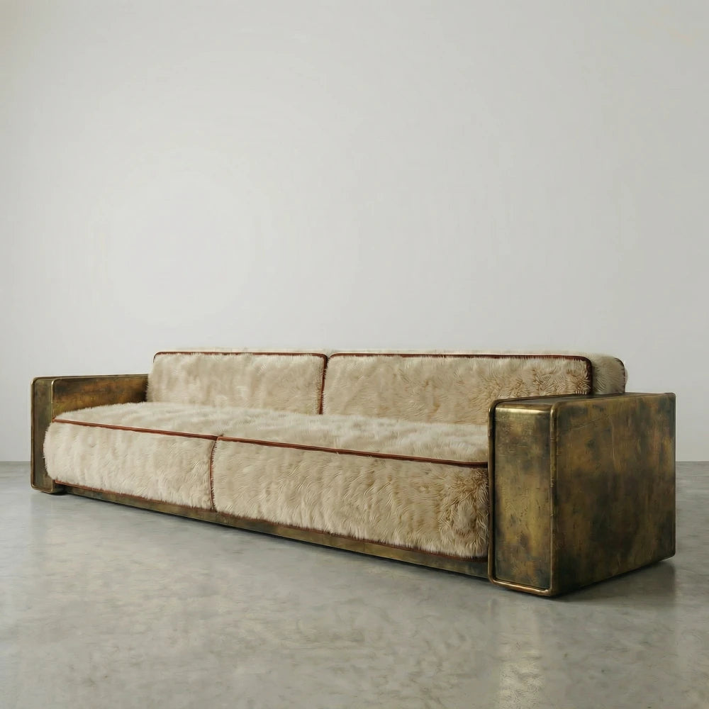 Three-quarter view of the Peau Sofa by Diamant Versatile, showing its low silhouette, cream upholstery and patinated gold-toned metal frame.