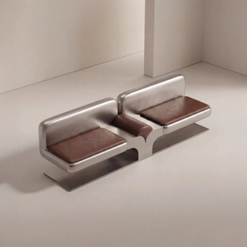 High-angle view of the Confluence bench by Diamant Versatile, with brown leather cushions and a sculptural brushed metal frame.