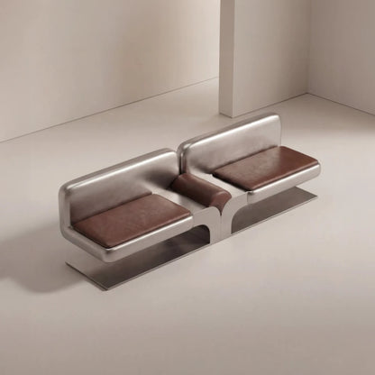 High-angle view of the Confluence bench by Diamant Versatile, with brown leather cushions and a sculptural brushed metal frame.