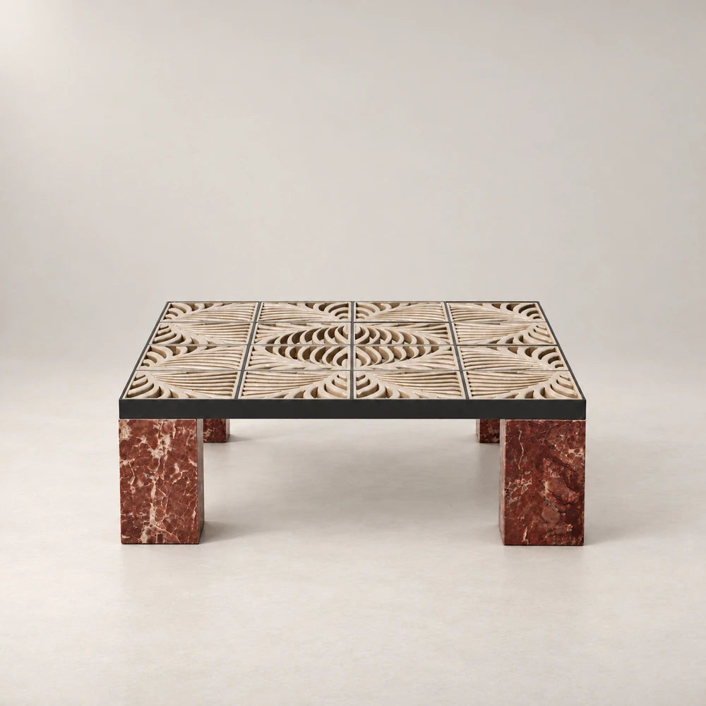 Front view of the Hikari Coffee Table by Eva Szumilas, showing its patterned beige stone top within a dark frame above red marble legs.