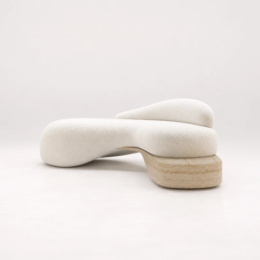 Infinity Sofa 01 by Eva Szumilas in textured ivory upholstery, with an organic curved seat, asymmetric backrest and rounded beige stone support beneath one end.