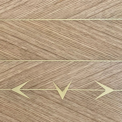 Macro detail of the oak DT01 Dining Table by Eva Szumilas, showing alternating diagonal wood grain, fine gold-toned lines and three directional arrow inlays.