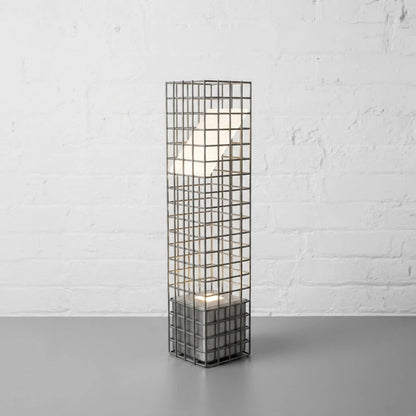 Ami Desk Lamp by Garnier Pingree in a stainless steel finish, with a tall grid frame surrounding an angled illuminated panel.