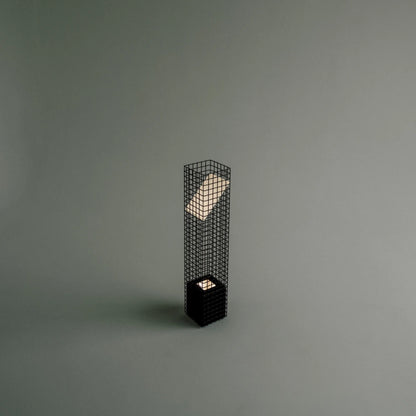 Elevated three-quarter view of the illuminated Ami Table Lamp by Garnier Pingree, showing its glowing angled panel and small light above the base.