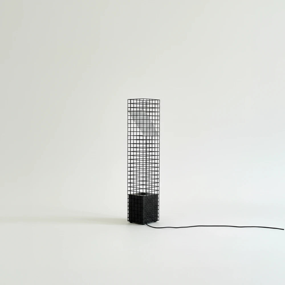 Unlit black Ami Table Lamp by Garnier Pingree against a pale background, showing its grid frame, angled panel and trailing black cable.