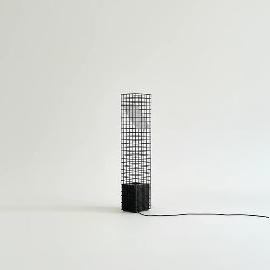 Unlit black Ami Table Lamp by Garnier Pingree against a pale background, showing its grid frame, angled panel and trailing black cable.