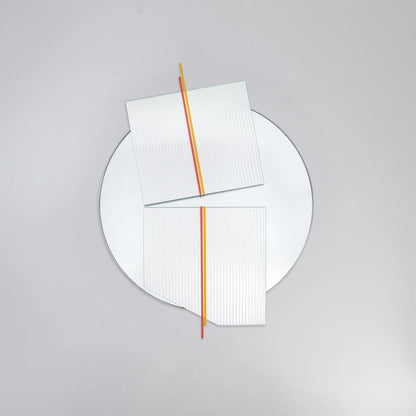 Front view of the large Claude Mirror by Garnier Pingree, showing red-orange and yellow rods, offset ribbed glass panels and a circular reflective surface.