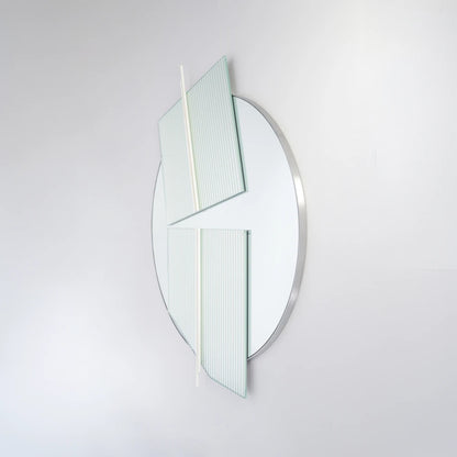 Angled view of the large Claude Mirror by Garnier Pingree, highlighting its projecting ribbed glass panels, white rods and slim silver-toned circular rim.