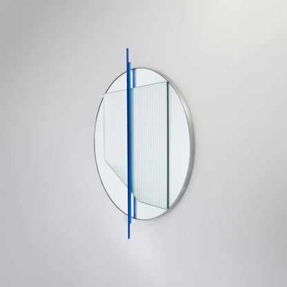 Angled view of the small Claude Mirror by Garnier Pingree, featuring blue vertical rods across a circular mirror and ribbed glass panel.