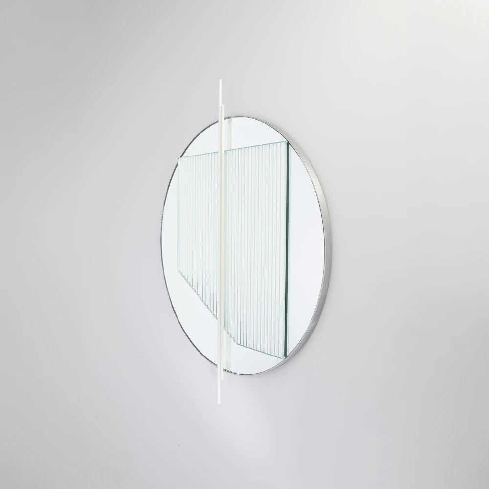 Angled view of the small Claude Mirror by Garnier Pingree, with white vertical rods, a ribbed glass panel and a slim circular rim.