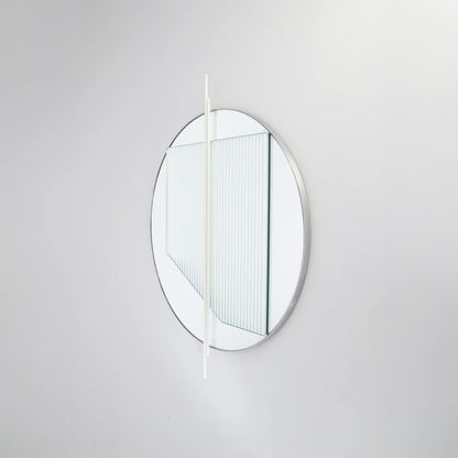 Angled view of the small Claude Mirror by Garnier Pingree, with white vertical rods, a ribbed glass panel and a slim circular rim.