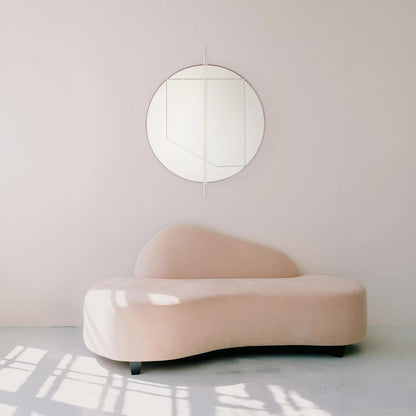 Small Claude Mirror by Garnier Pingree with white vertical rods, mounted above a curved pale pink sofa in a sunlit interior.