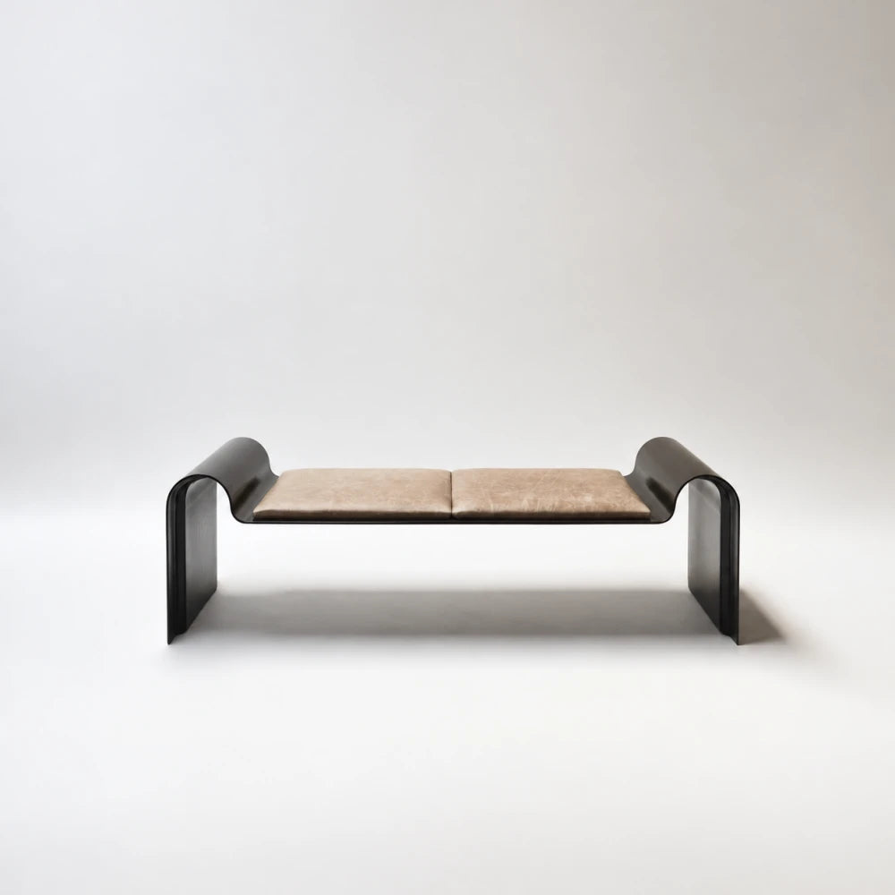 Front view of the Monarch Bench by Garnier Pingree, with two tan seat cushions and a dark metal frame curving into broad legs.