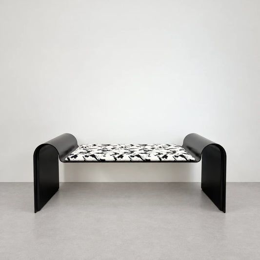 Front view of the Monarch Bench by Garnier Pingree, with a black-and-white patterned cushion and black metal ends curving into wide legs.