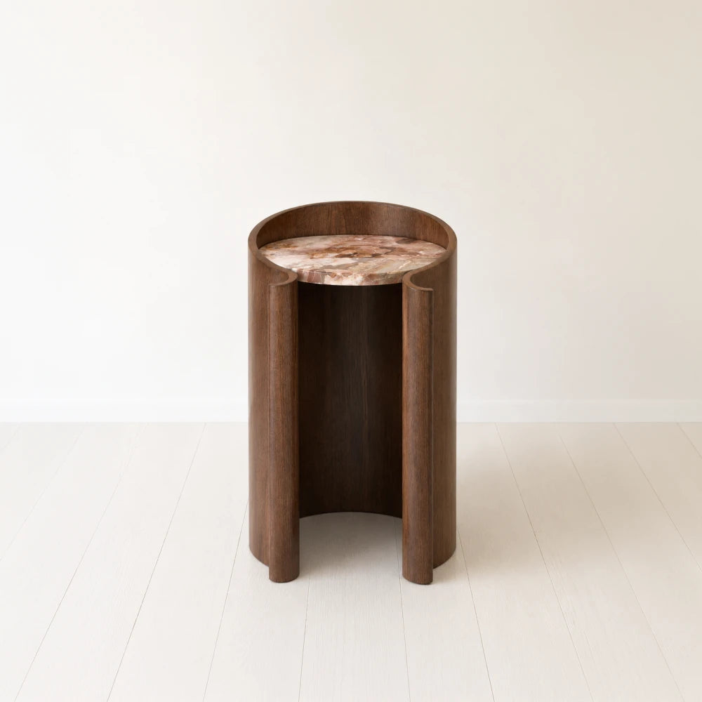 Front view of the Volute Side Table by Garnier Pingree, with a dark wooden shell, scrolling edges and a pink-and-brown veined stone top.