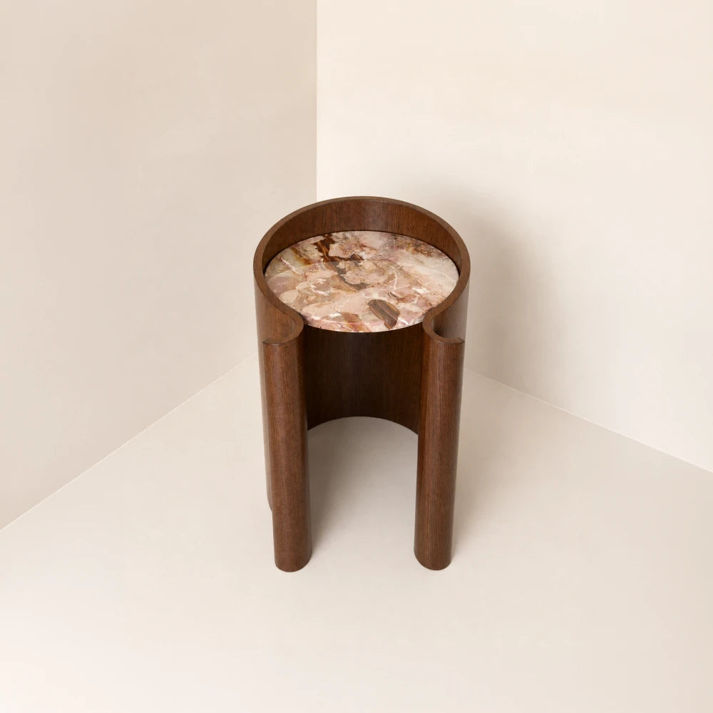 Elevated front view of the Volute Side Table by Garnier Pingree, revealing its multicoloured stone top and open curved wooden base.