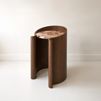 Closer view of the Volute Side Table by Garnier Pingree, highlighting its rounded wooden scrolls, open front and pink-and-brown stone tabletop.