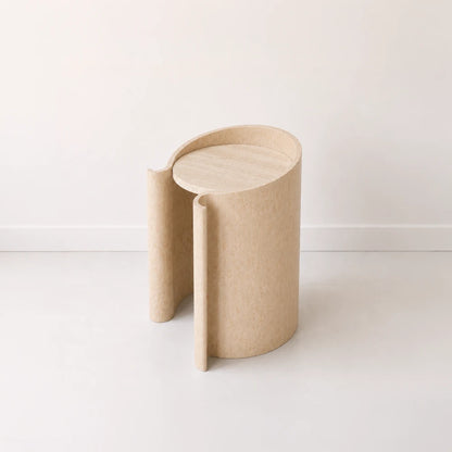 Volute Side Table by Garnier Pingree in the pale Dune finish, with a circular travertine top and curved shell with scrolling edges.