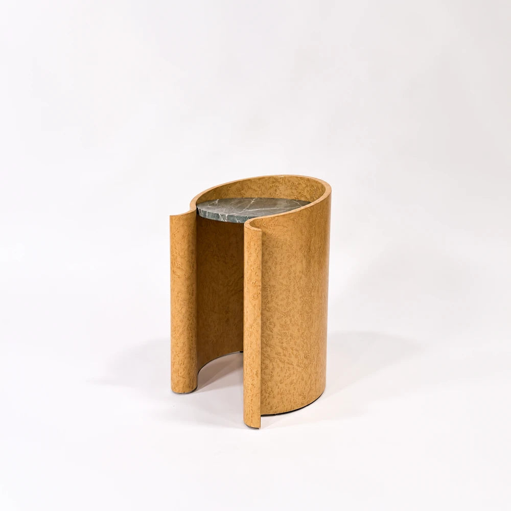 Three-quarter view of the maple Volute Side Table by Garnier Pingree, with figured wood grain, an open front and a recessed stone top.