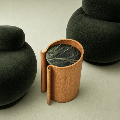 Maple Volute Side Table by Garnier Pingree between two dark green lounge chairs, with a circular green veined stone top.