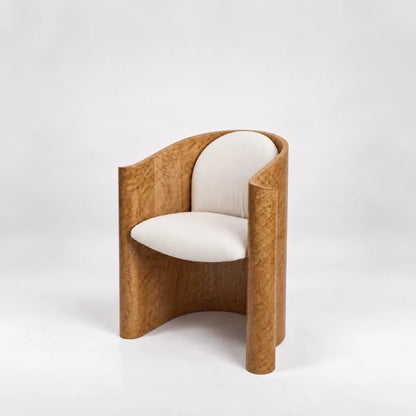 Three-quarter view of the Volute Chair by Garnier Pingree, with cream upholstery, golden wood grain and curved sides extending to the floor.