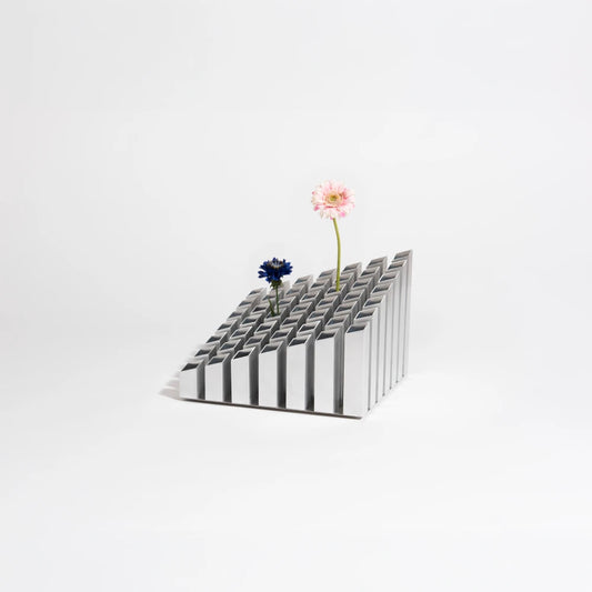 Cinquante decorative object by Malvin Gaborit in a silver finish, displayed with two flowers against a white background.