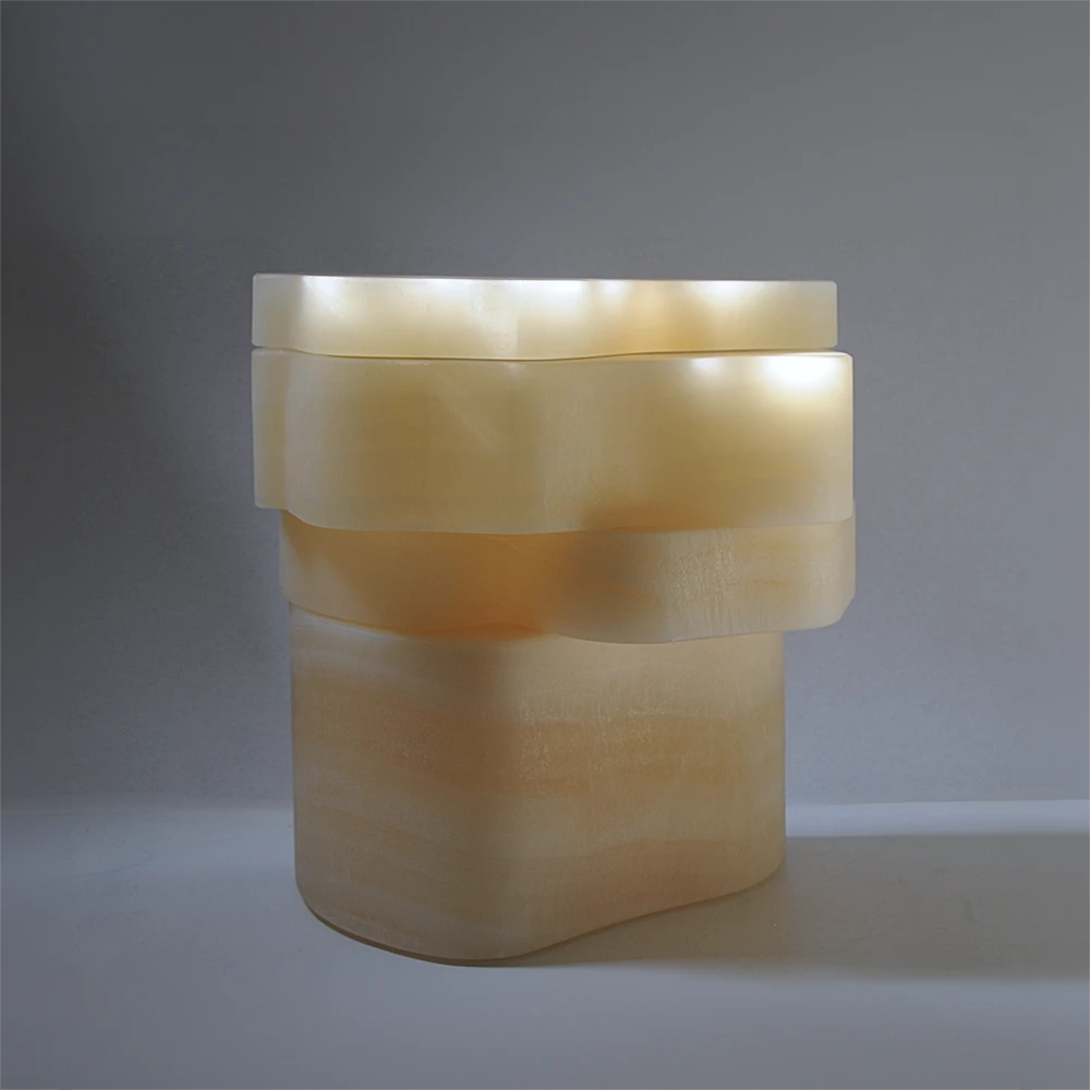 Three-quarter view of the closed White Moth Nightstand by Panorammma in softly illuminated white onyx