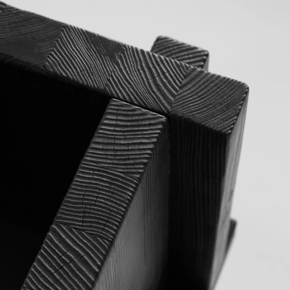 Close-up of the Itooraba Chair Black by Sizar Alexis, highlighting the burned pine grain, end-grain patterns and intersecting wooden panels.