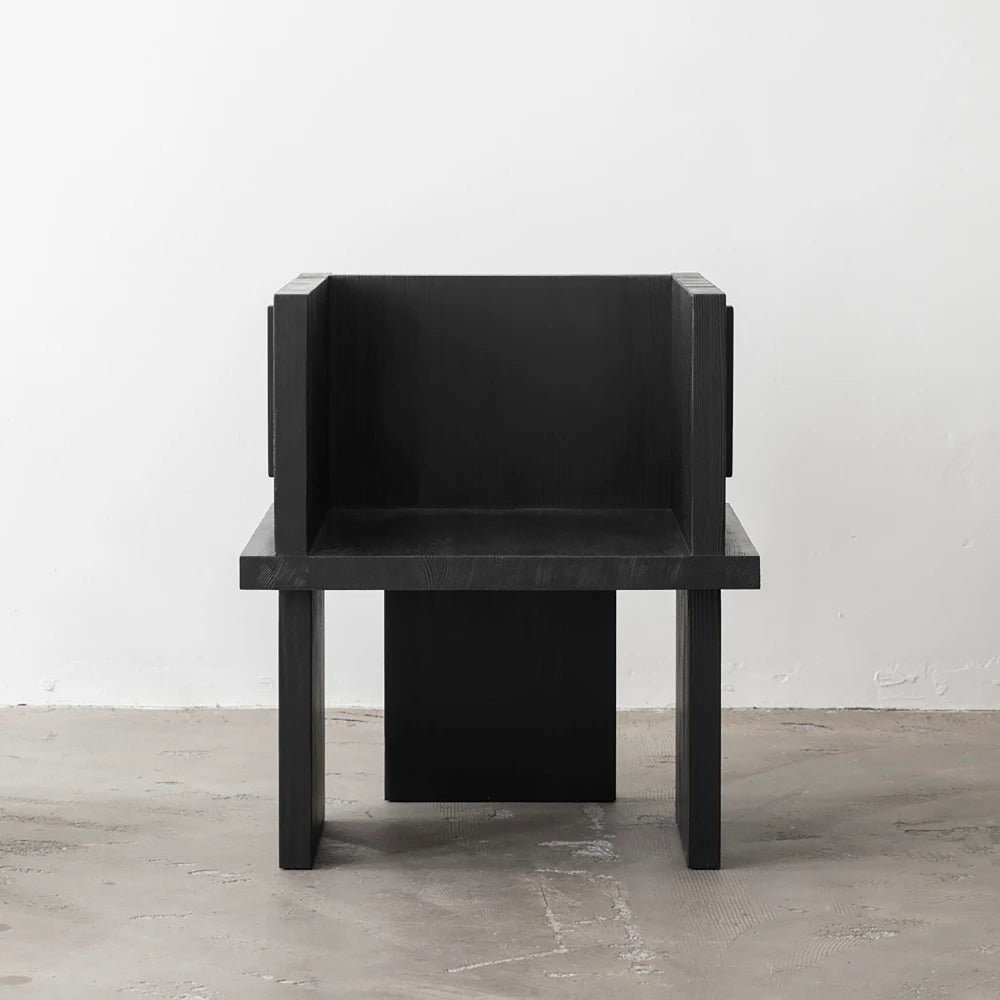 Front view of the Itooraba Chair Black by Sizar Alexis, showing its enclosed seat, broad armrests and asymmetric slab legs.