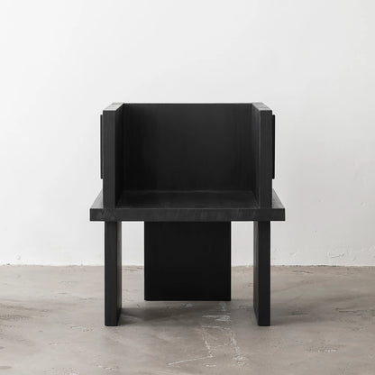 Front view of the Itooraba Chair Black by Sizar Alexis, showing its enclosed seat, broad armrests and asymmetric slab legs.