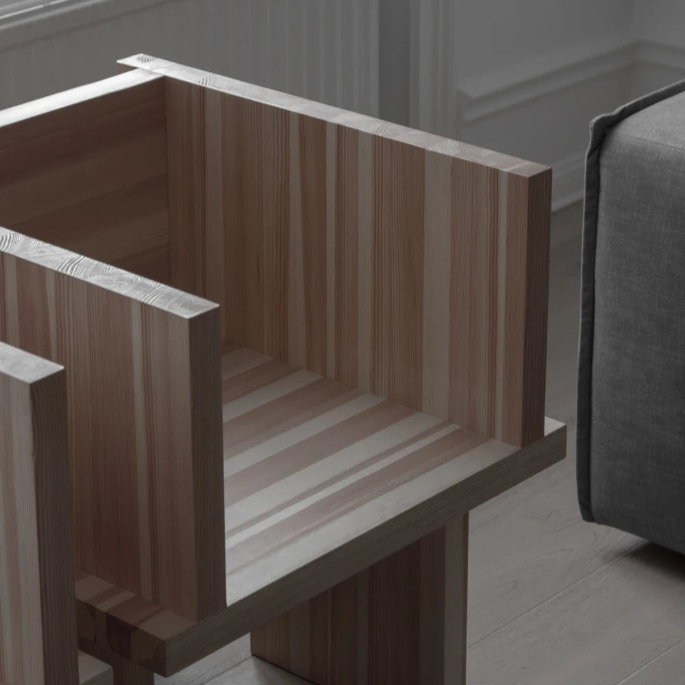 Close-up of the Itooraba Chair by Sizar Alexis in an interior, showing the striped pine grain across its seat and backrest.