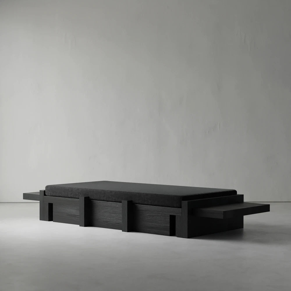 Three-quarter view of the Itooraba Daybed by Sizar Alexis, highlighting its dark cushion, extended side platforms and geometric wooden structure.