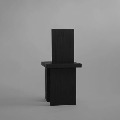 Rear view of the Itooraba Chair by Sizar Alexis, featuring a tall rectangular backrest and asymmetric burned pine slab legs.