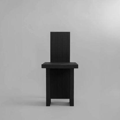 Front view of the Itooraba Chair by Sizar Alexis, emphasizing its narrow silhouette and architectural burned pine construction.