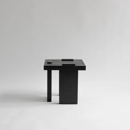 Side view of the Itooraba Stool Black by Sizar Alexis, showing its geometric silhouette and contrasting narrow and broad supports.