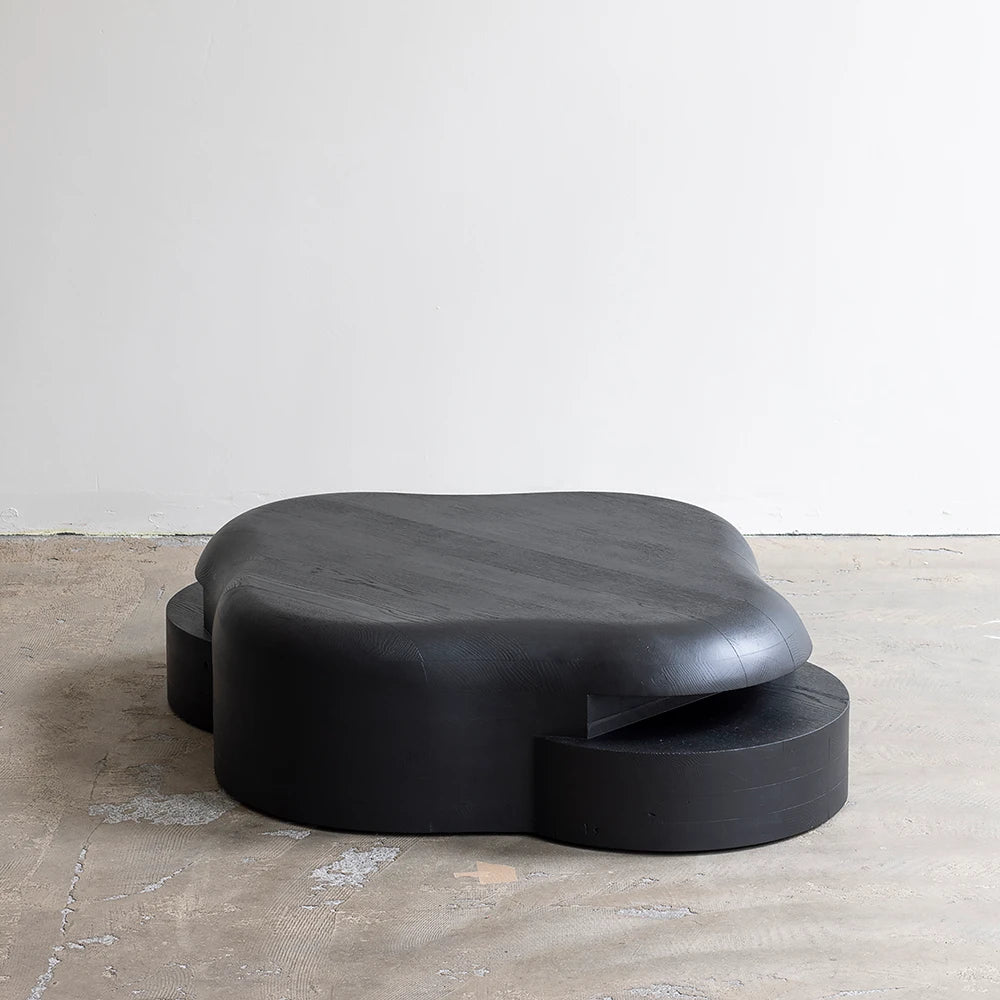Three-quarter view of the Lahmu Coffee Table by Sizar Alexis, showing its broad rounded top and offset circular base elements.