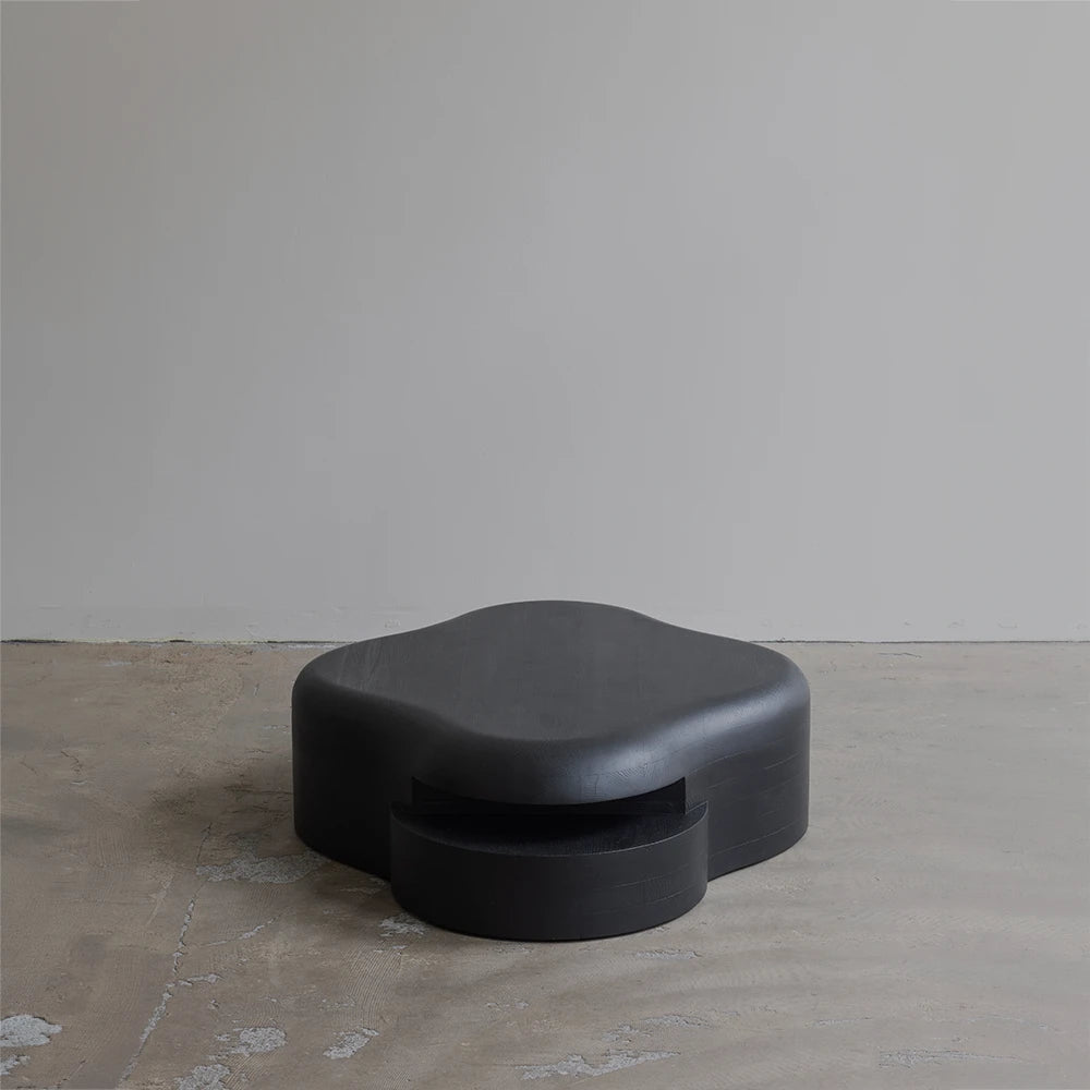 Front three-quarter view of the Lahmu Coffee Table by Sizar Alexis, emphasizing its low profile, curved top, and recessed base.