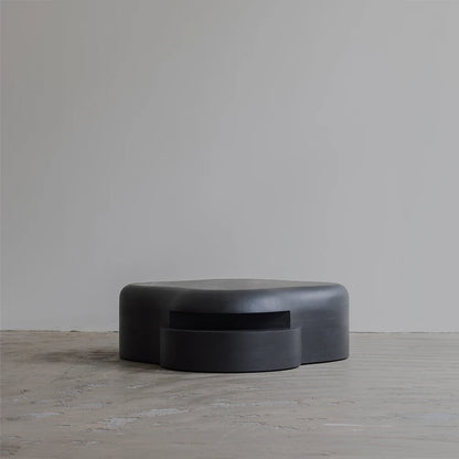 Low frontal view of the Lahmu Coffee Table by Sizar Alexis, defined by a monolithic black form and projecting circular element.