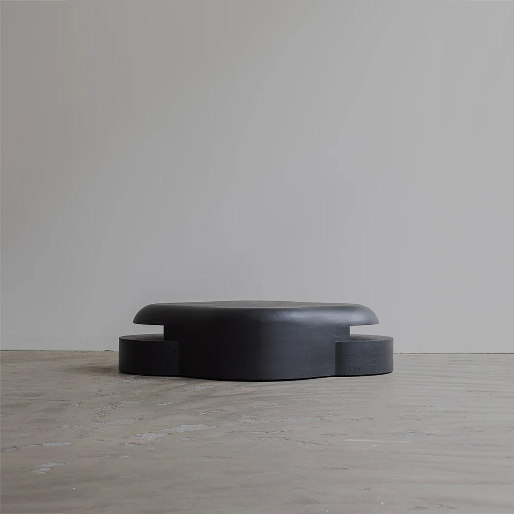 Rear view of the Lahmu Coffee Table by Sizar Alexis, revealing its extended rounded tabletop and symmetrically projecting lower sections.
