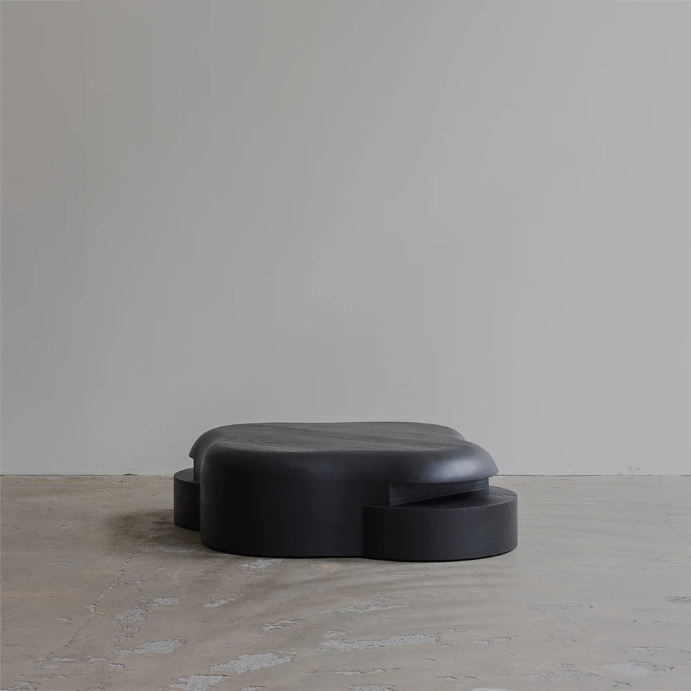 Opposite three-quarter view of the Lahmu Coffee Table by Sizar Alexis, showcasing its layered construction, curved silhouette, and dark wood grain.