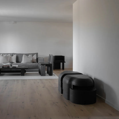 Lahmu Large Console Black by Sizar Alexis positioned against a wall in a minimalist living room with coordinating black furniture.