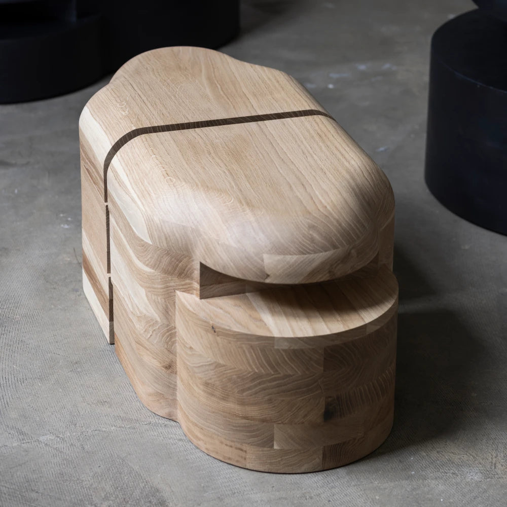 Three-quarter close view of the Lahmu Stool Natural by Sizar Alexis, revealing its rounded top, layered base, and sculptural opening.
