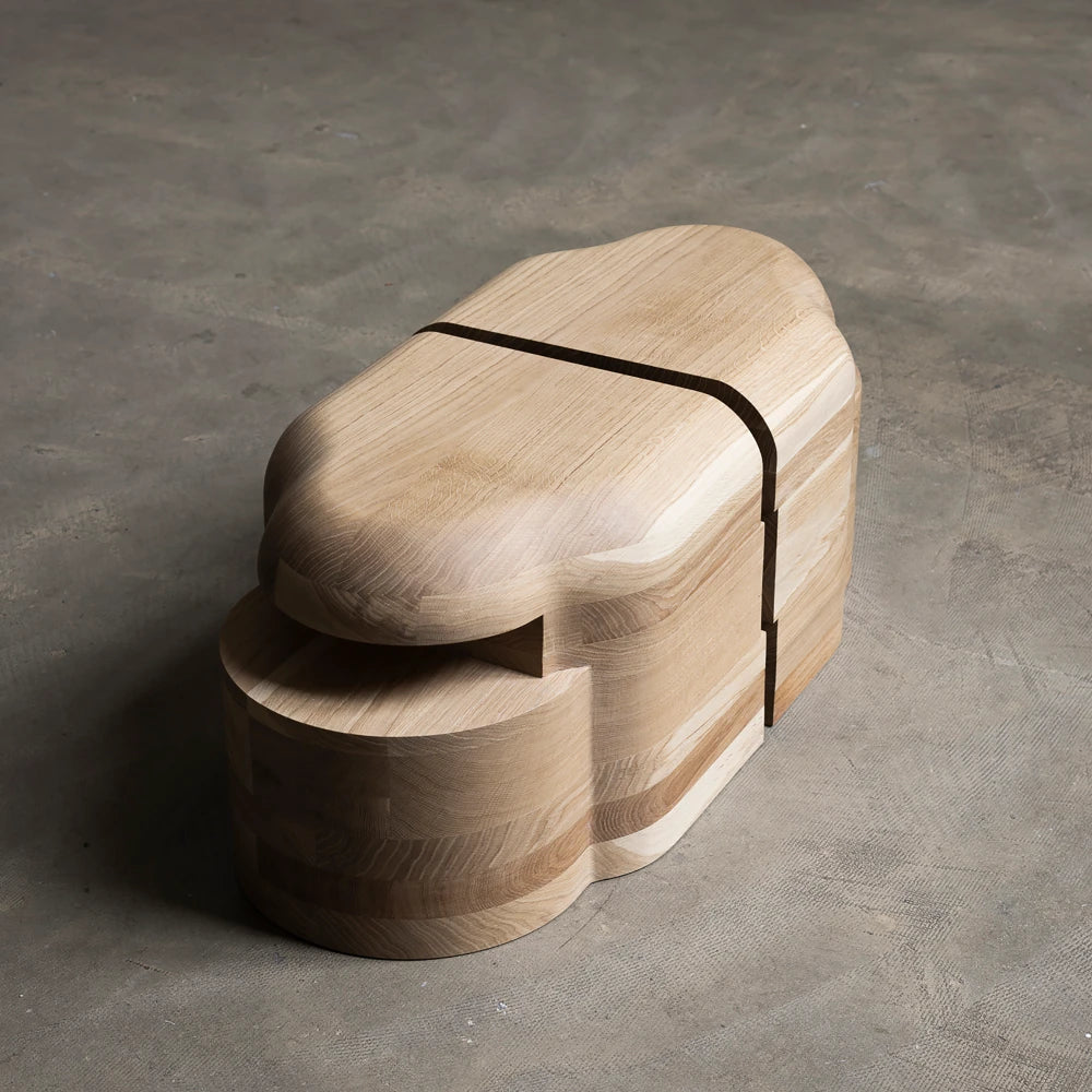 Lahmu Stool Natural by Sizar Alexis in a high three-quarter view, showcasing smooth oak curves, visible grain, and dark inset line.