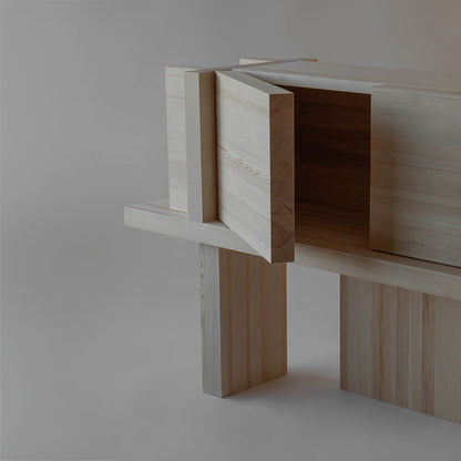 Three-quarter view of the Itooraba Sideboard Natural by Sizar Alexis with one door open, revealing its storage compartment and architectural base.