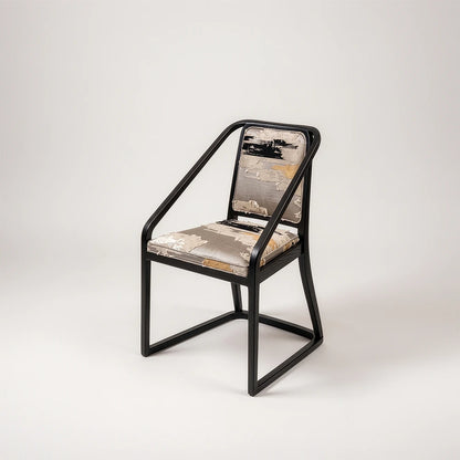Oblation Dining Chair by Studio Romell, featuring a black wooden frame, sloping armrests and textured upholstery in grey, cream, black and ochre.