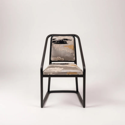 Front view of the Oblation Dining Chair by Studio Romell, highlighting its angular black wooden frame and abstract patterned seat and back cushions.