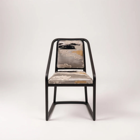 Front view of the Oblation Dining Chair by Studio Romell, highlighting its angular black wooden frame and abstract patterned seat and back cushions.