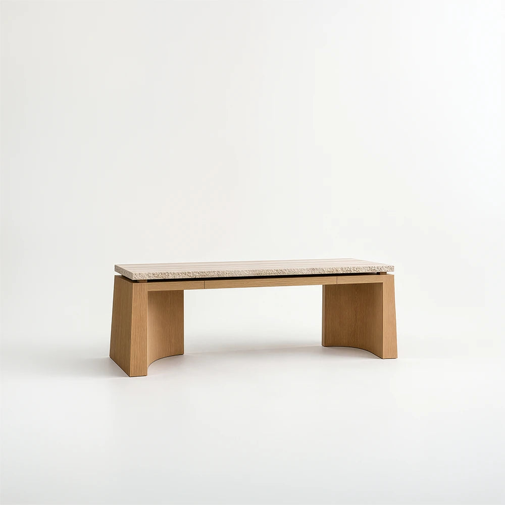 Santos Desk by Studio Romell, featuring a pale stone top with a textured edge, flush drawer fronts and wooden supports with curved inner surfaces.