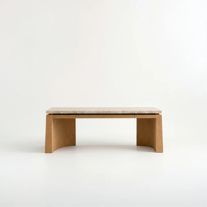 Front view of the Santos Desk by Studio Romell, showing its slim drawer fronts, pale stone desktop and symmetrical wooden supports with curved inner faces.